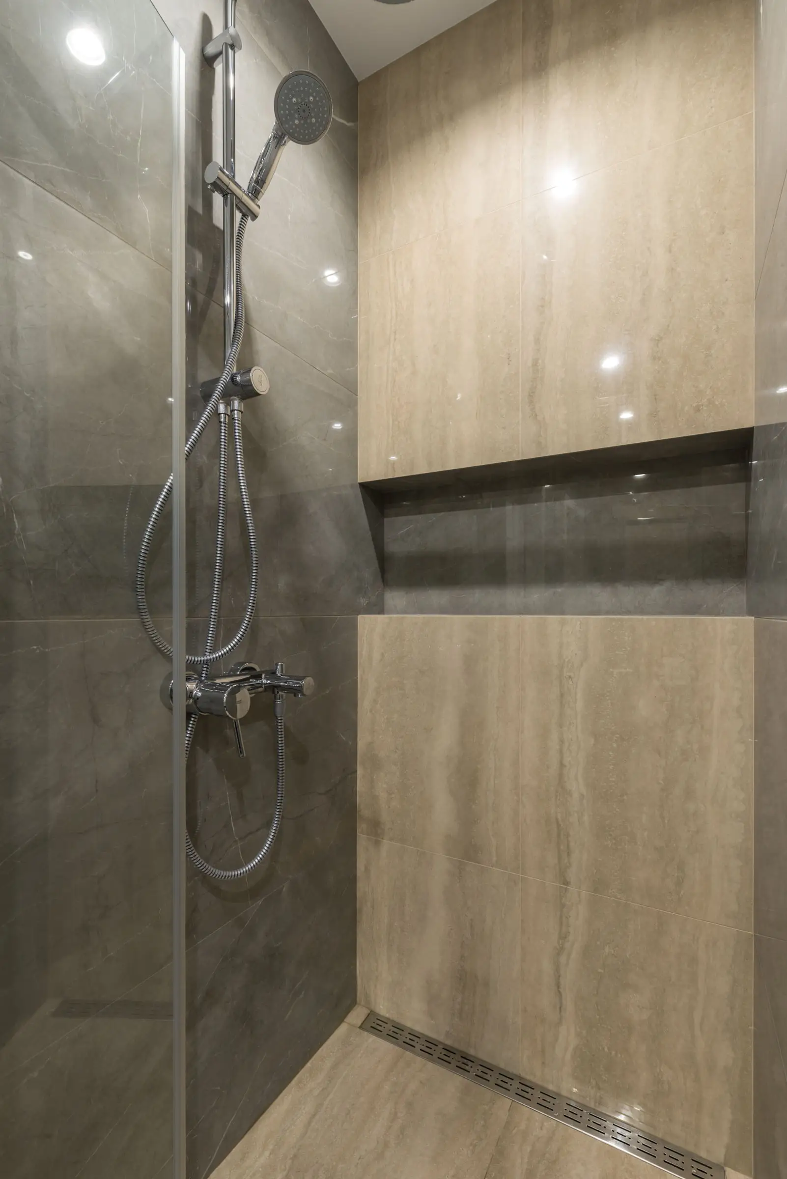 Douche de plain-pied en pierre grise avec caniveau linéaire au sol et niche encastrée sur toute la largeur