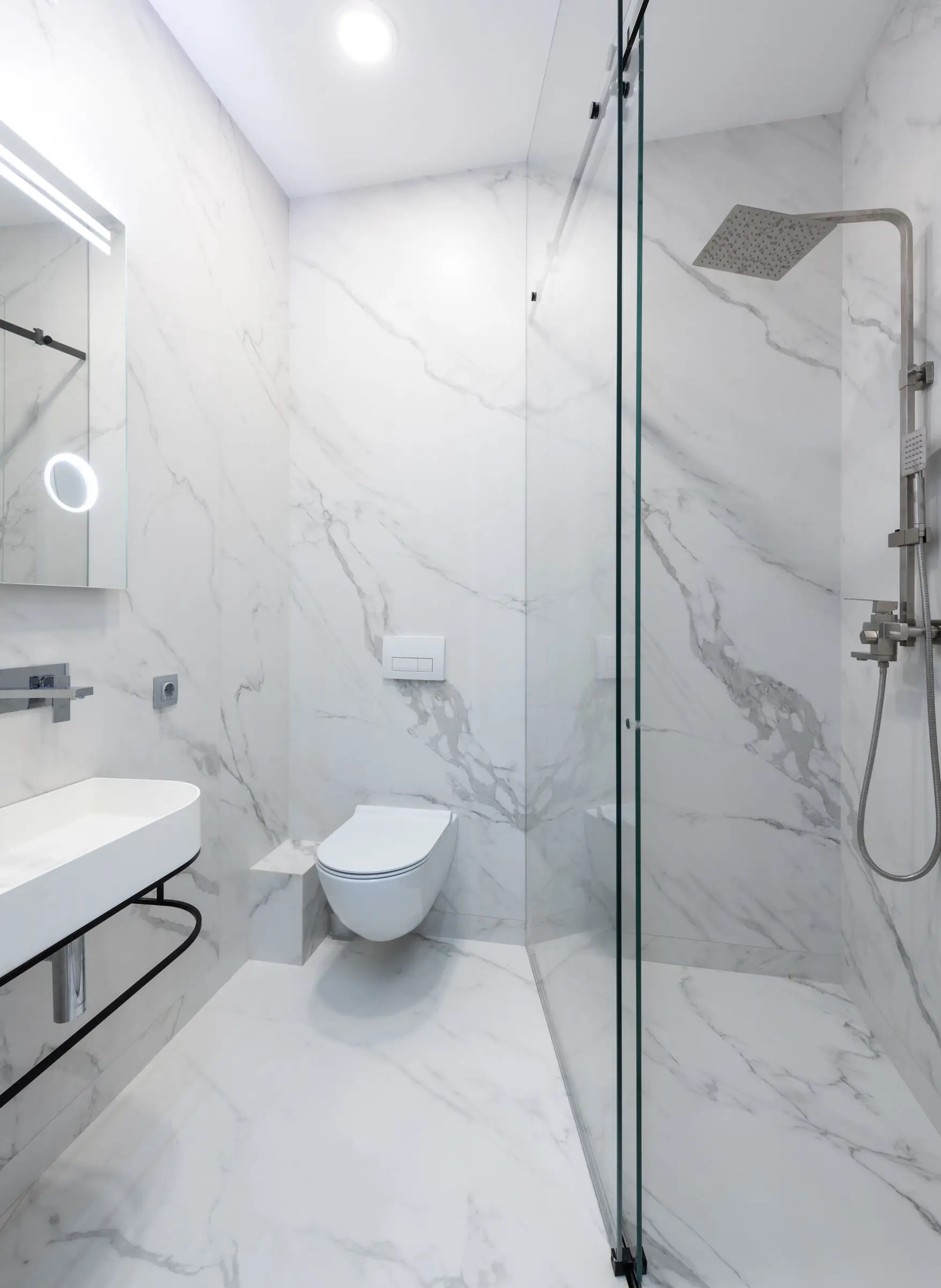 Douche de plain-pied en quartzite blanc veiné de gris, paroi de verre sans cadre, sol continu jusqu’au lavabo suspendu