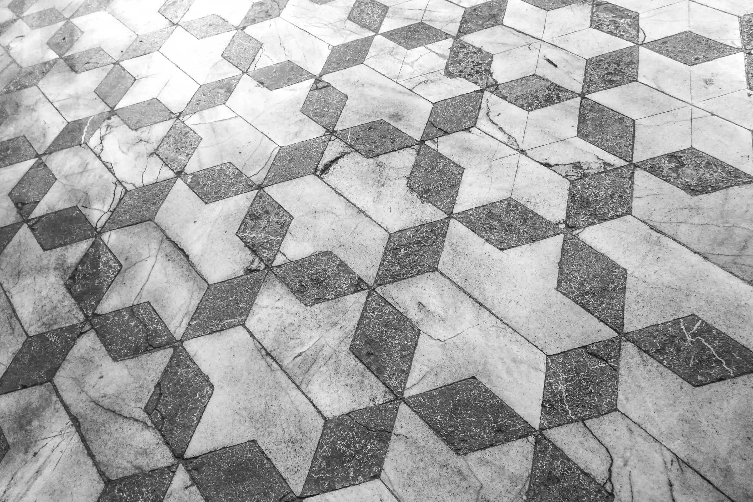 Sol ancien en marbre blanc et gris posé en motif d’étoiles, terni, rayé et fissuré